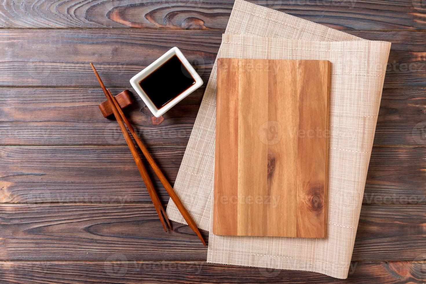 leeg rechthoekig houten bord voor sushi met saus en eetstokjes Aan houten tafel, top visie foto