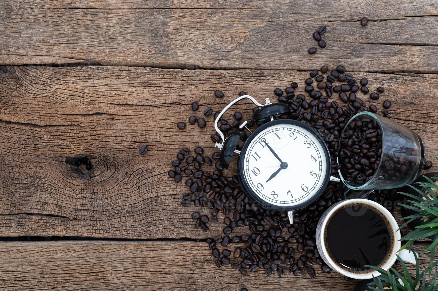 wekker, een mok koffie en koffiebonen op het bureau foto