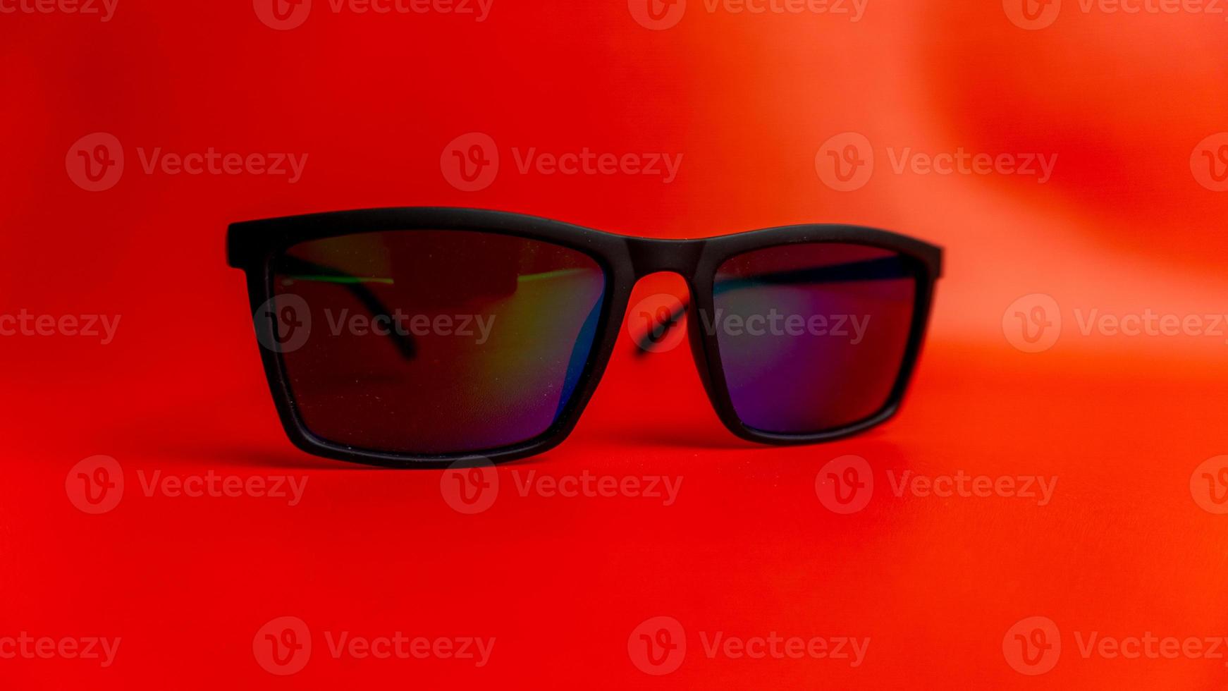 zwart zonnebril Aan rood achtergrond foto