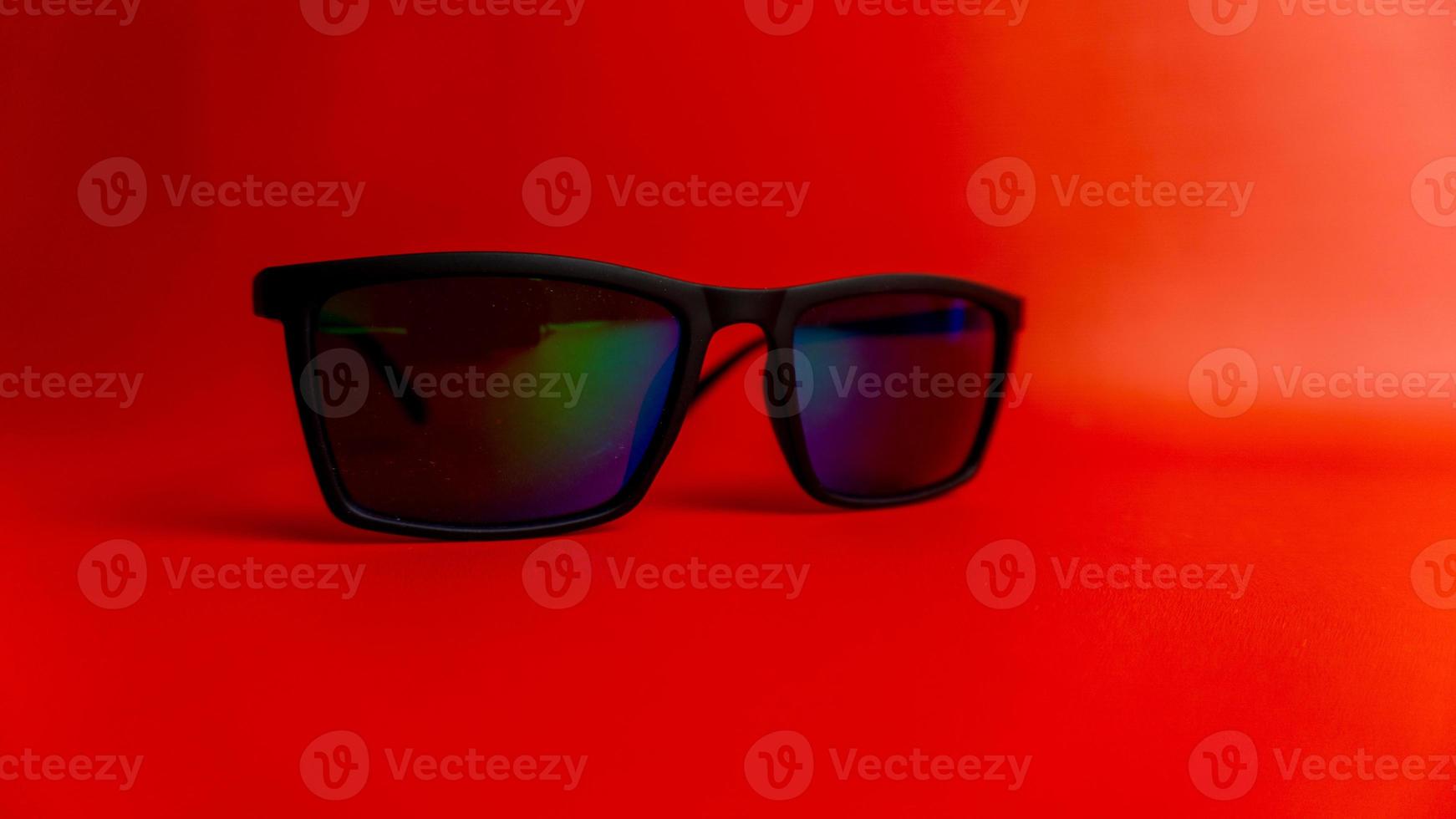 zwart zonnebril Aan rood achtergrond foto