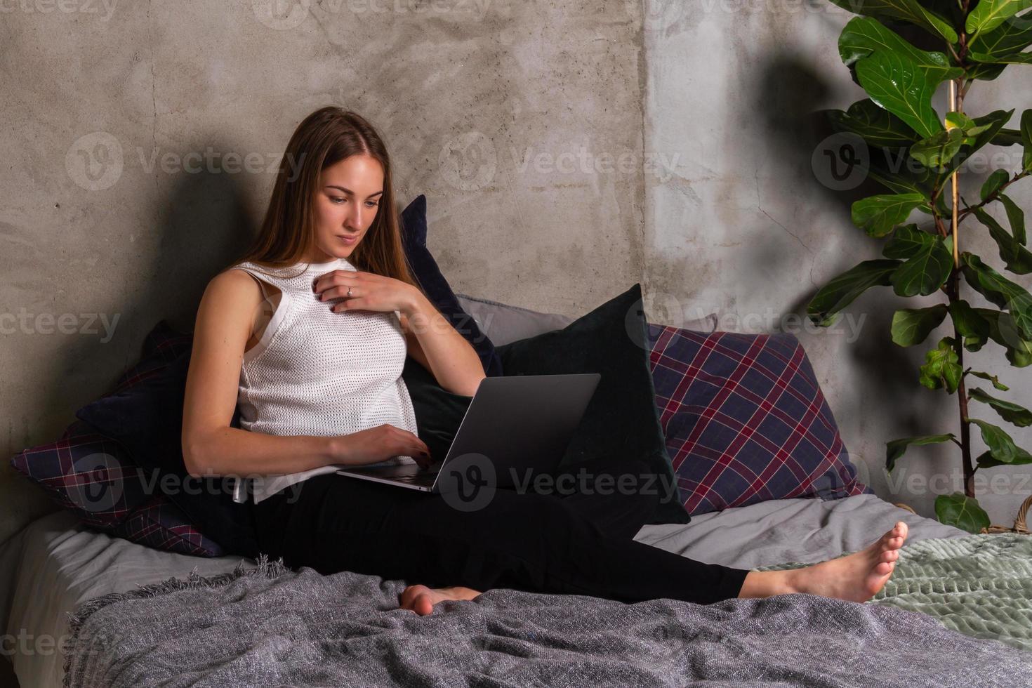 vrouw zittend Aan bed en werken Aan een laptop foto