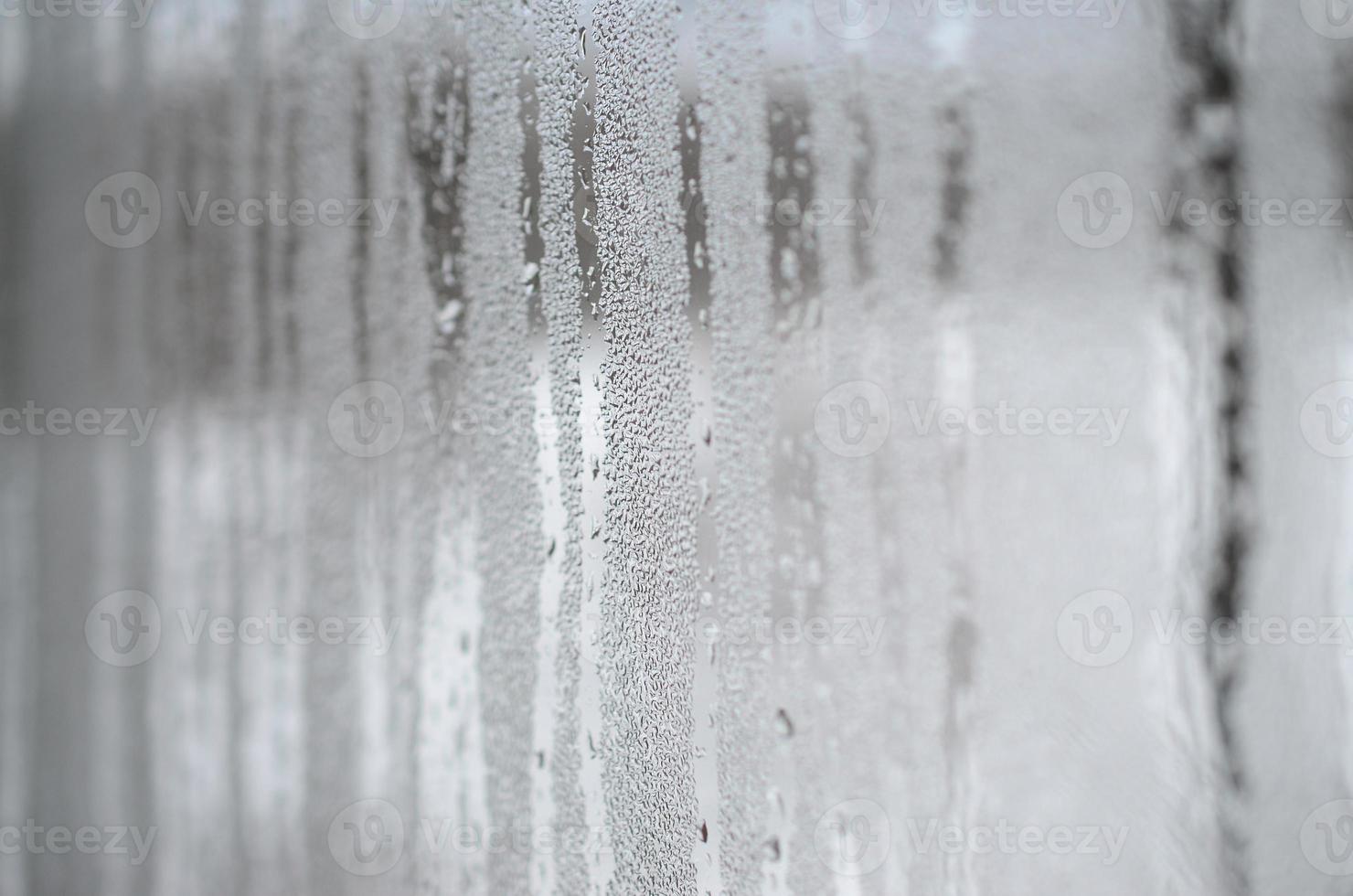 de structuur van een beneveld glas met een veel van druppels en condensatie stromen. achtergrond beeld foto