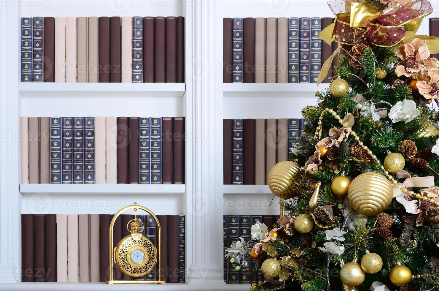 een mooi versierd Kerstmis boom Aan de achtergrond van een boekenplank met veel boeken van verschillend kleuren en gouden klok. Kerstmis achtergrond beeld van de bibliotheek foto