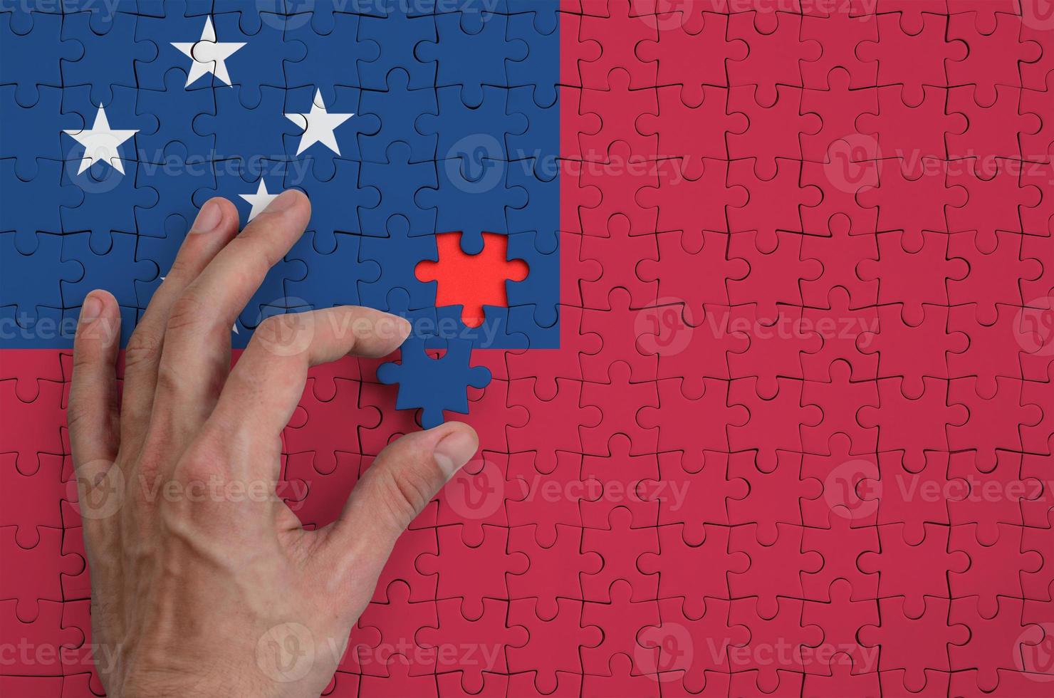 Samoa vlag is afgebeeld Aan een puzzel, welke de man's hand- voltooit naar vouwen foto