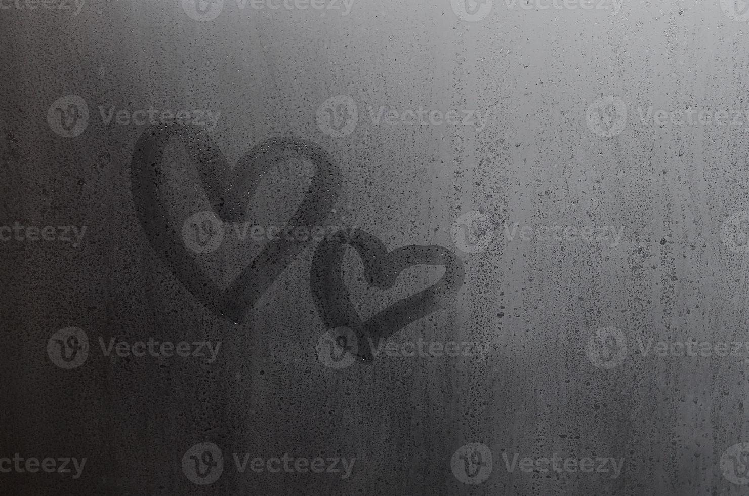 paar van abstract wazig liefde hart symbool getrokken door hand- Aan de nat venster glas met zonlicht achtergrond. sjabloon voor Valentijn dag ansichtkaarten foto