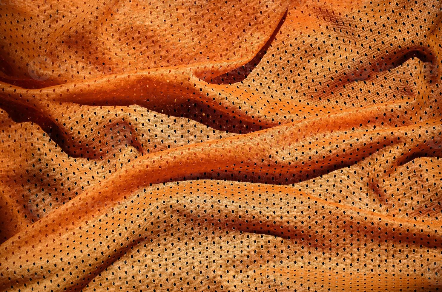 dichtbij omhoog van oranje polyester nylon- sportkleding shorts naar gemaakt een getextureerde achtergrond foto