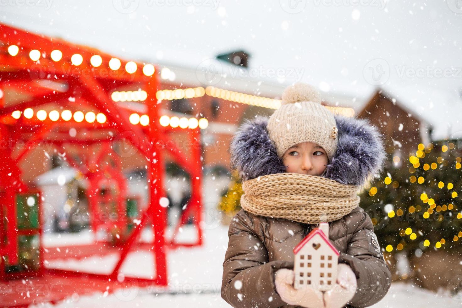 huis, miniatuur huisje in handen van meisje vervelend wanten en warm kleren buitenshuis in sneeuw. familie waarden, aankoop huisvesting, verhuizing, hypotheek. knus huis, kerstmis, nieuw jaar reservering foto