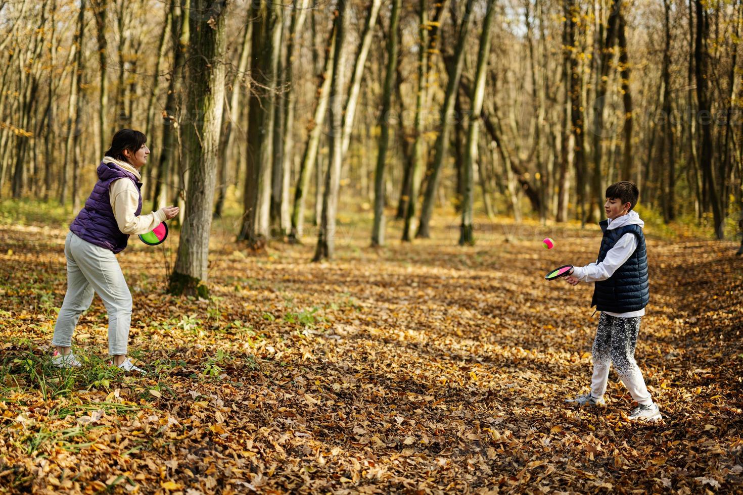 moeder met zoon Speel in herfst Woud vangst en toss bal spel. foto