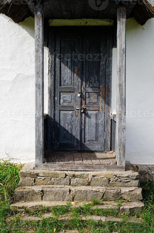 oud verweerd deur in de houten muur van een oude hut foto