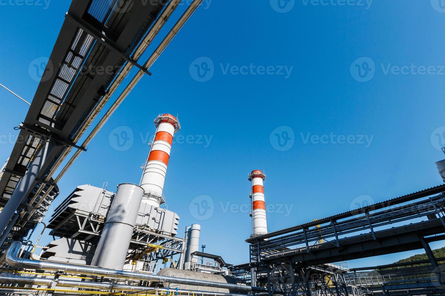 gas- turbine macht fabriek Aan natuurlijk gas- met schoorstenen van rood Wit kleur tegen een blauw lucht Aan een zonnig dag foto