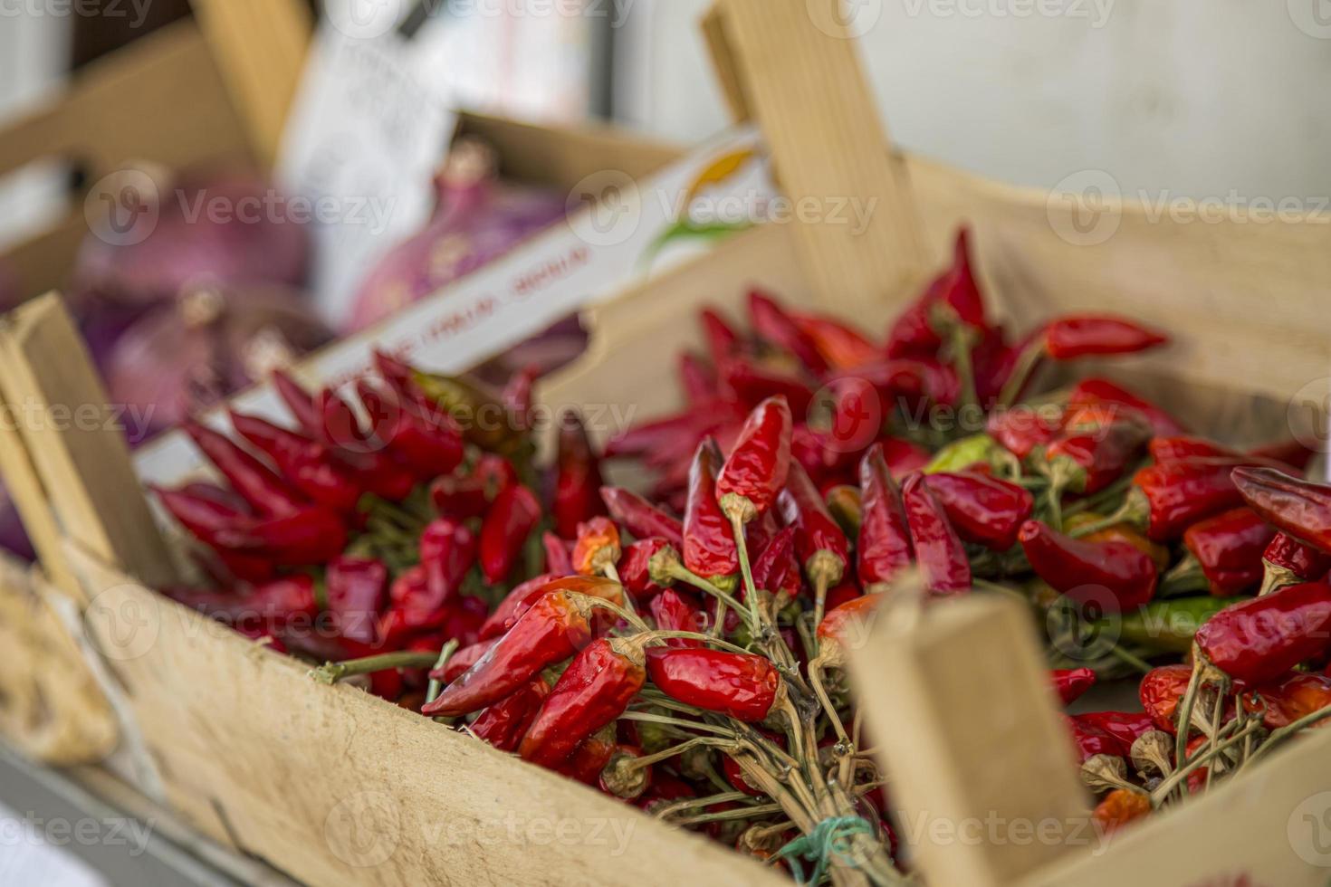 houten dozen vol van helder rood Chili paprika's Aan de Open markt in Italië. foto