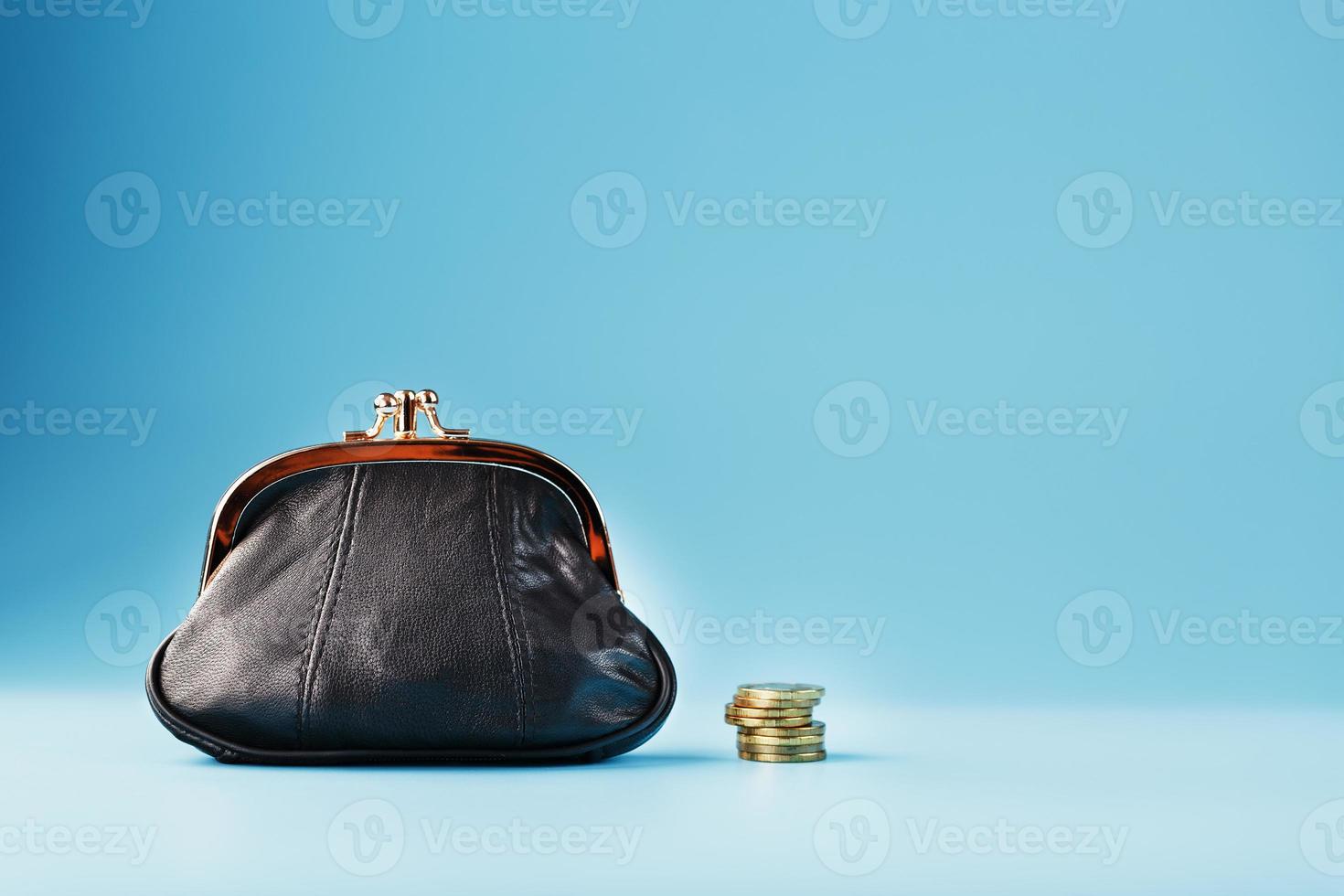zwart portemonnee met munten Aan een blauw achtergrond. begroting voor investering in de toekomst. foto