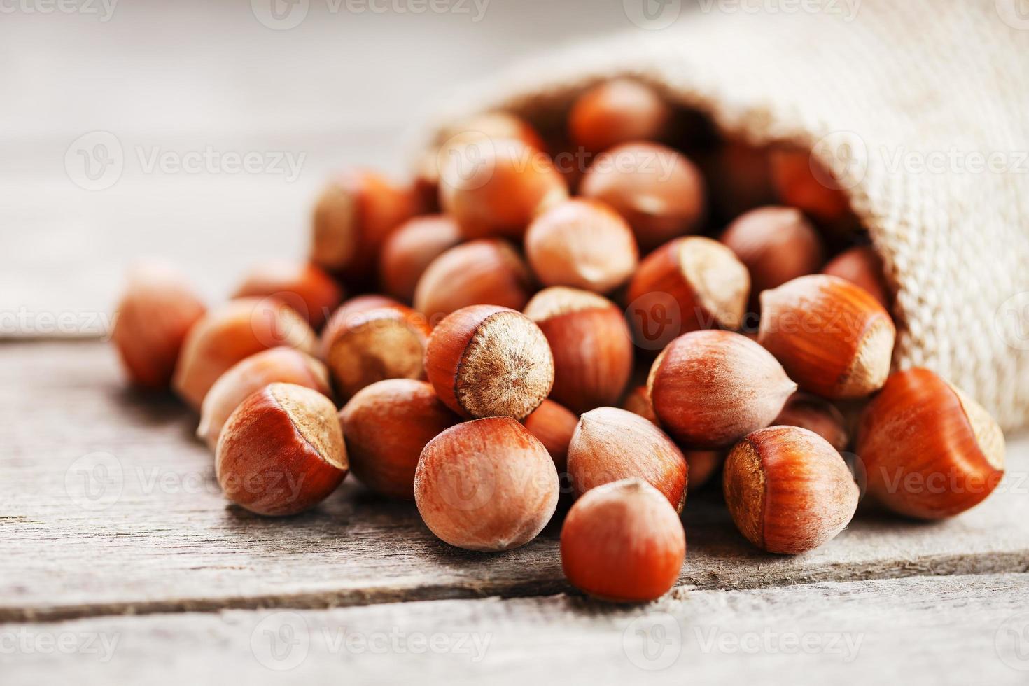 hazelnoten in een omslag, gegoten uit van een zak van jute Aan een grijs houten tafel foto