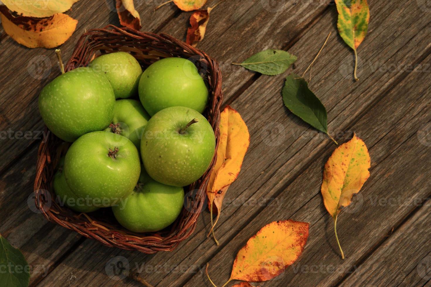 appel op houten tafel met gevallen herfstbladeren foto