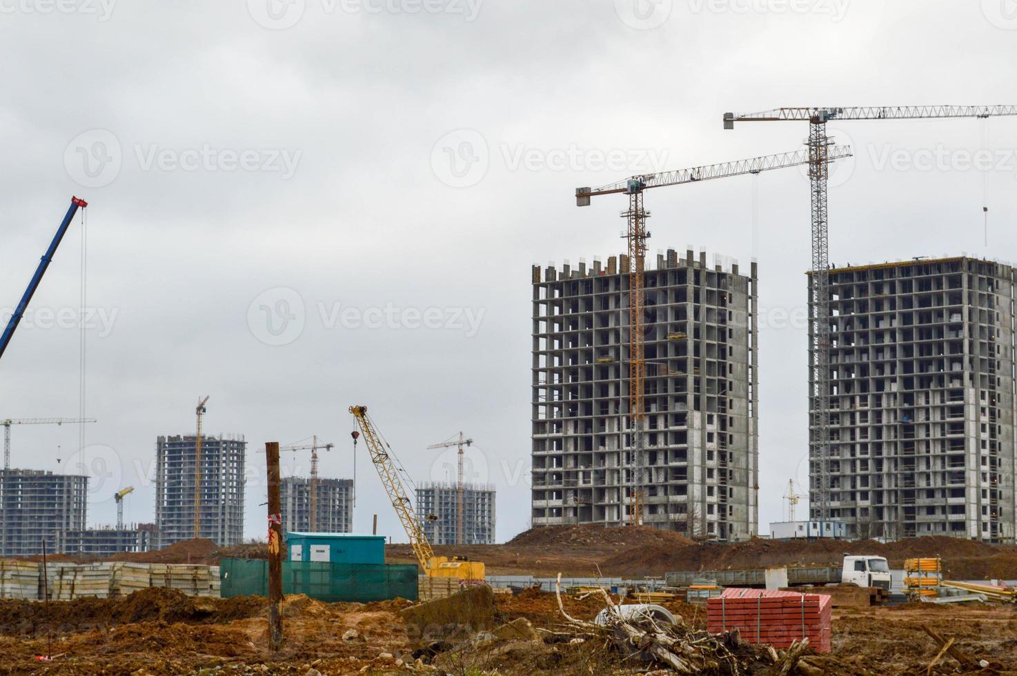 bouw van een nieuw microdistrict met hoog huizen, nieuw gebouwen met ontwikkelde infrastructuur met de helpen van groot industrieel kranen en professioneel bouw uitrusting in een groot stad foto