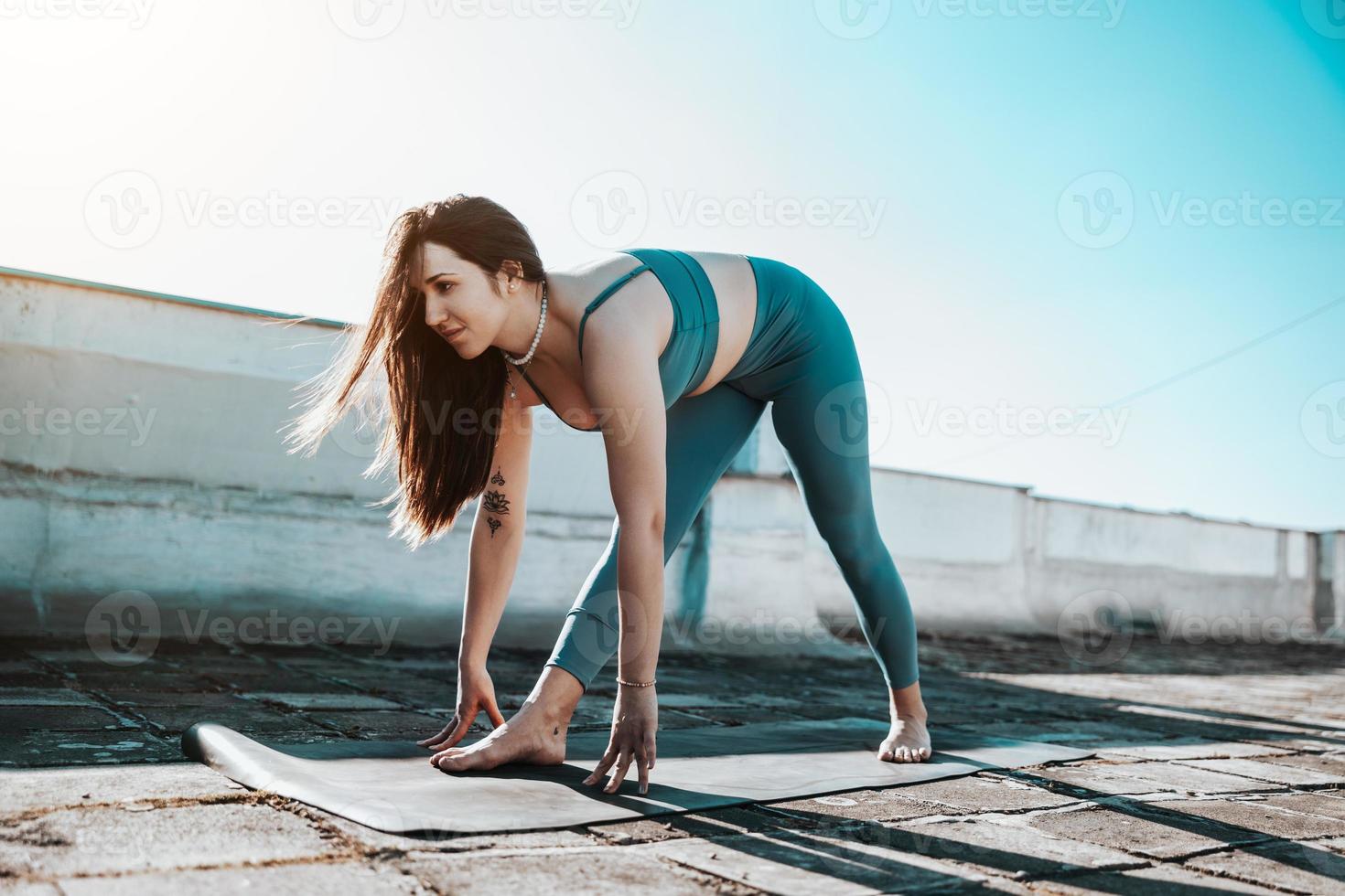 vrouw uitrekken buitenshuis terwijl aan het doen training Aan een op het dak terras foto