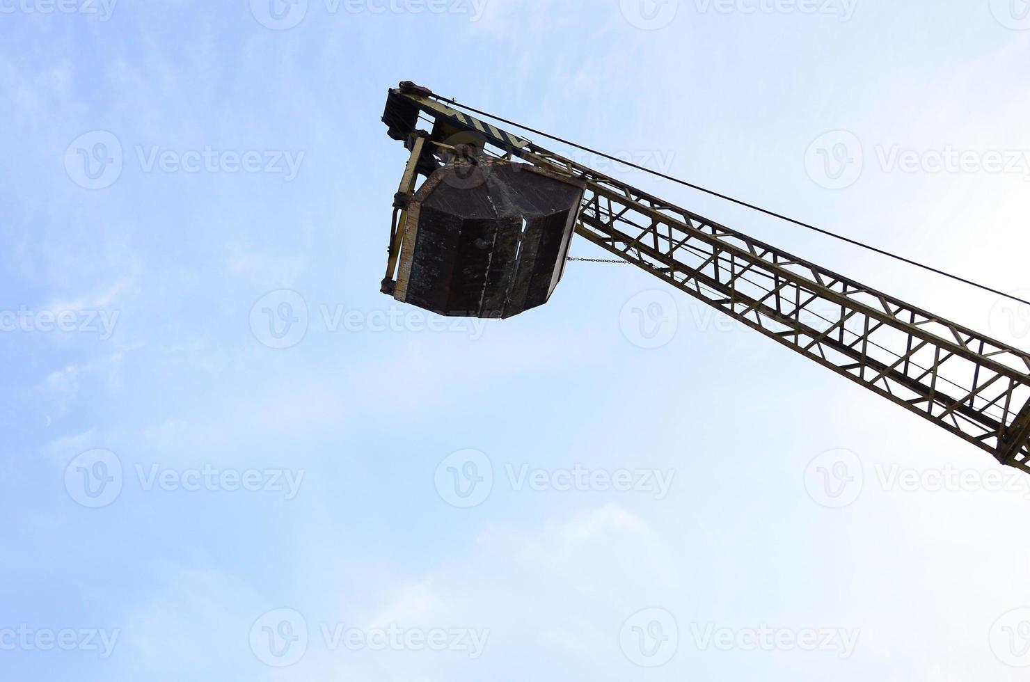 oud geel mechanisch clamshell grijp Aan blauw lucht achtergrond foto