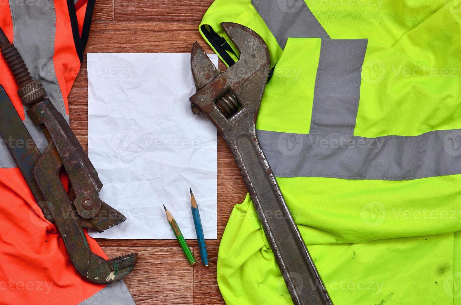 een verfrommeld vel van papier met twee potloden omringd door groen en oranje werken uniformen en verstelbaar sleutels foto