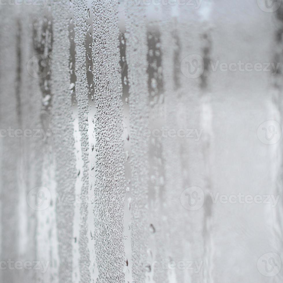 de structuur van een beneveld glas met een veel van druppels en condensatie stromen. achtergrond beeld foto
