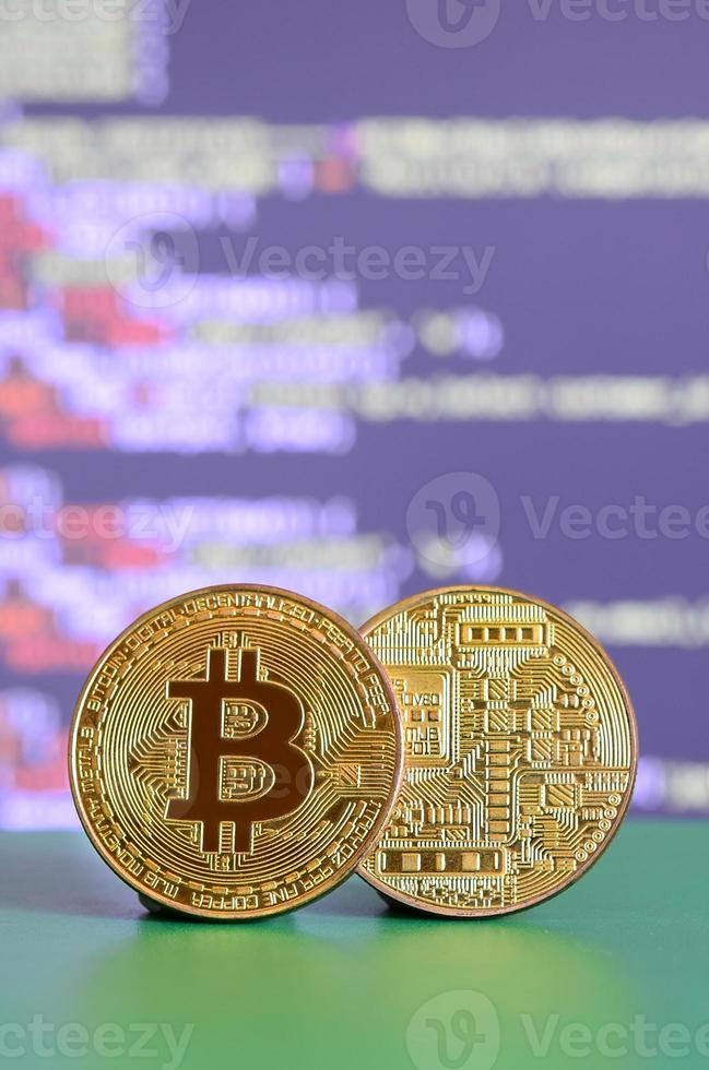 twee goud bitcoins liggen Aan de groen oppervlakte Aan de achtergrond van de Scherm, welke shows de werkwijze van mijnbouw de crypto valuta foto