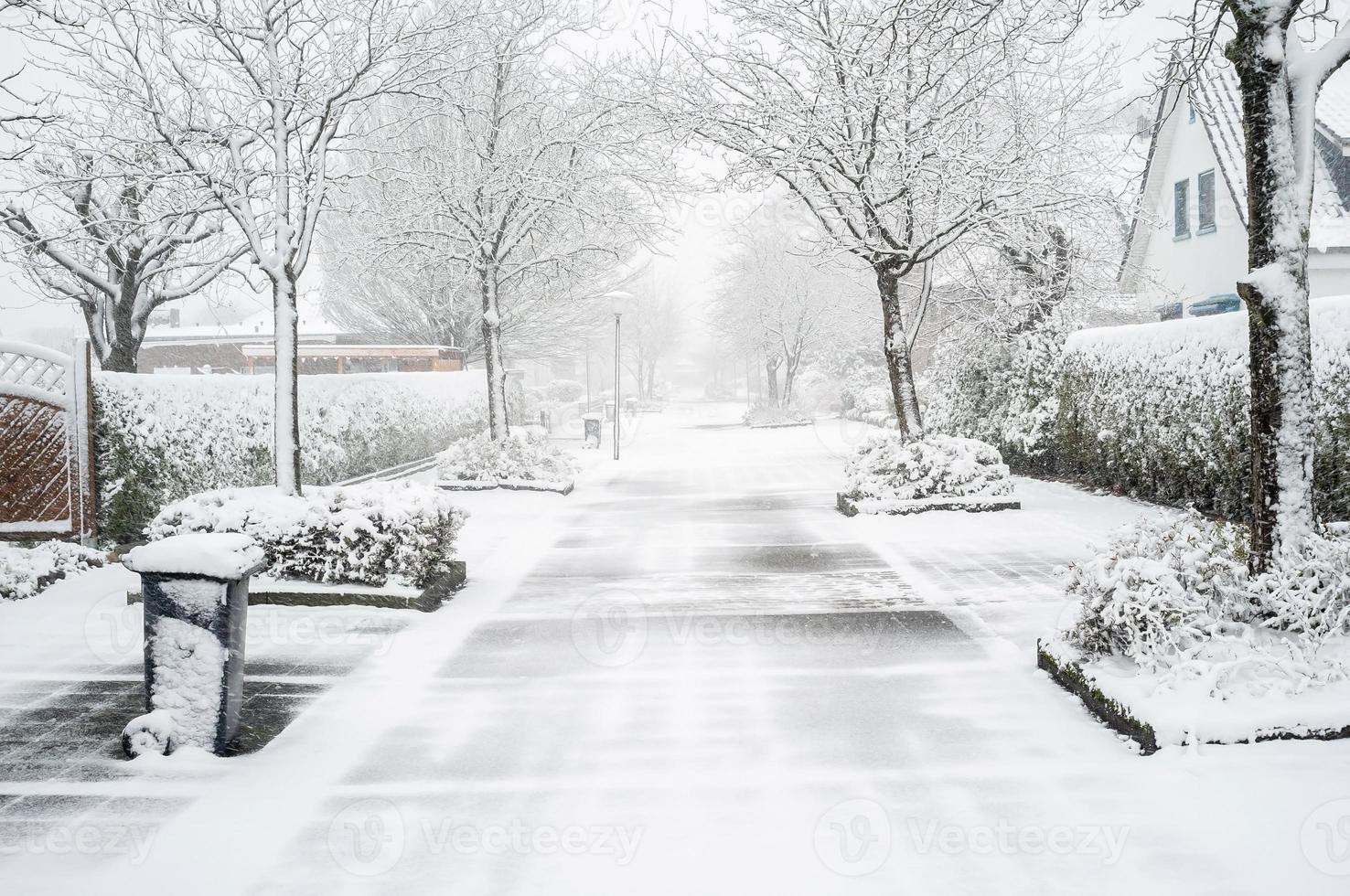 met sneeuw bedekt Europese stad, weg Aan de straat met privaat huizen en bomen foto