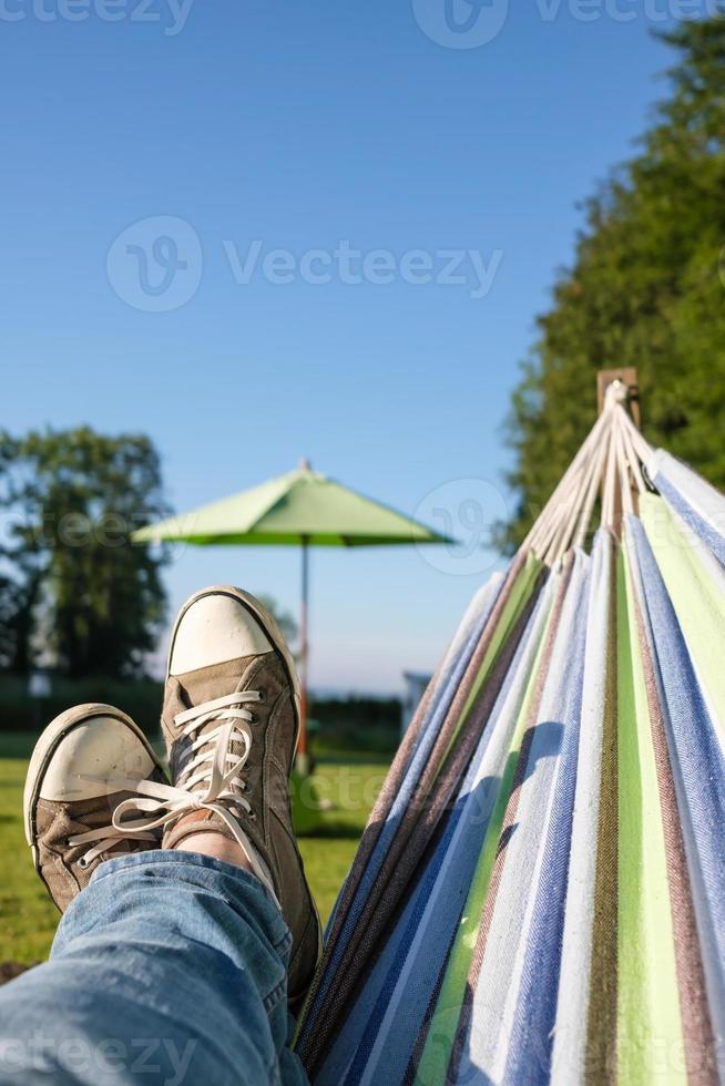 mannetje poten in sportschoenen en jeans in een hangmat, Aan een warm zomer dag, camping. levensstijl. foto