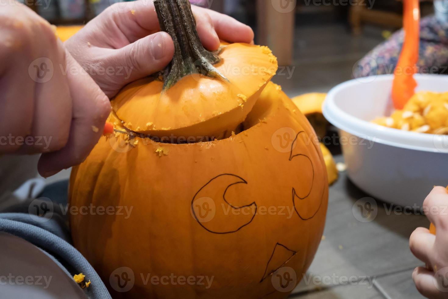 halloween voorbereiding. familie snijwerk pompoen in jack-o-lantern terwijl zittend Aan de vloer, in de huis. foto