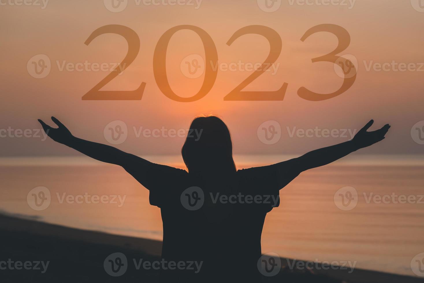 2023 gelukkig nieuw jaar concept, gezond vrouw verheven hand- Holding 2023 karakter tekst Bij zonsopkomst Aan de strand. foto