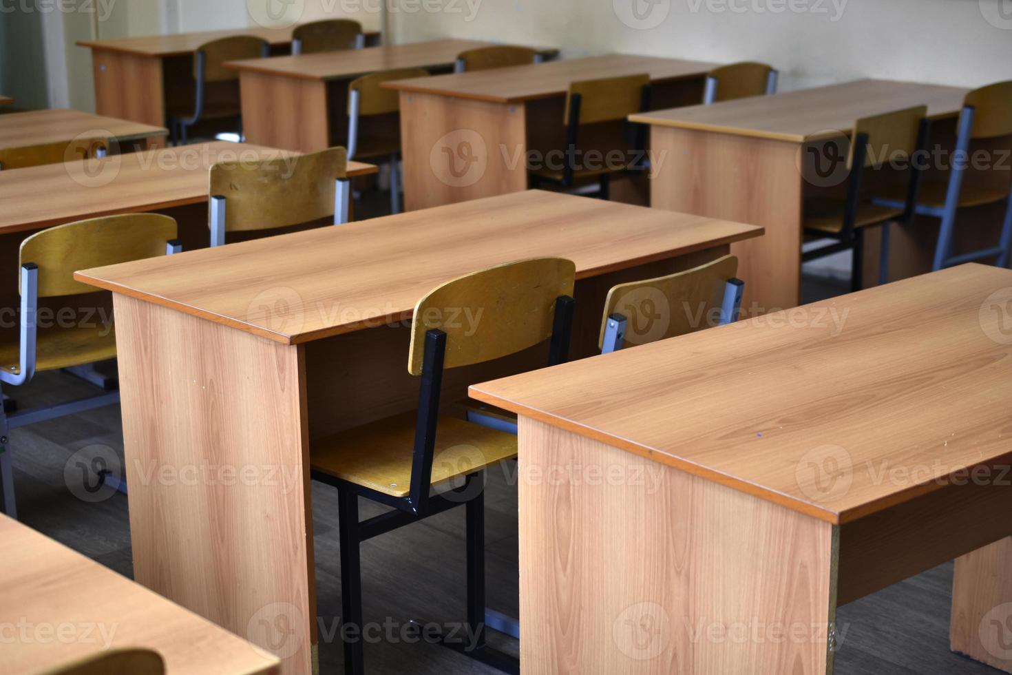 school- benodigdheden. onderwijs concept. school- bureaus en stoelen in een studenten klas Bij school.t foto