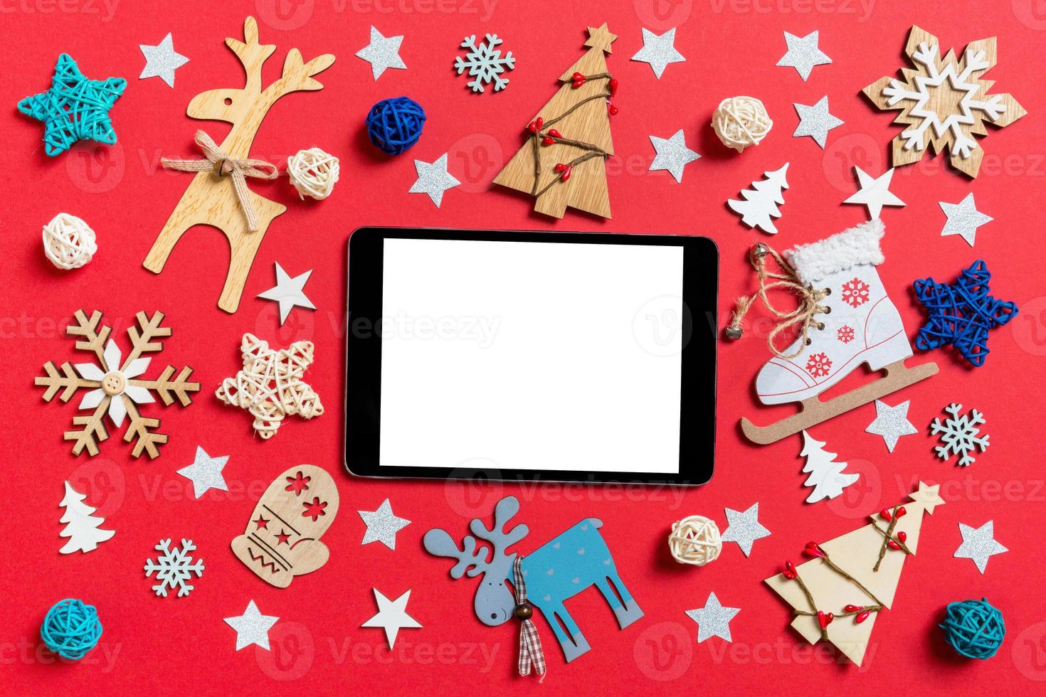 top visie van digitaal tablet, vakantie speelgoed en decoraties Aan rood Kerstmis achtergrond. nieuw jaar tijd concept foto