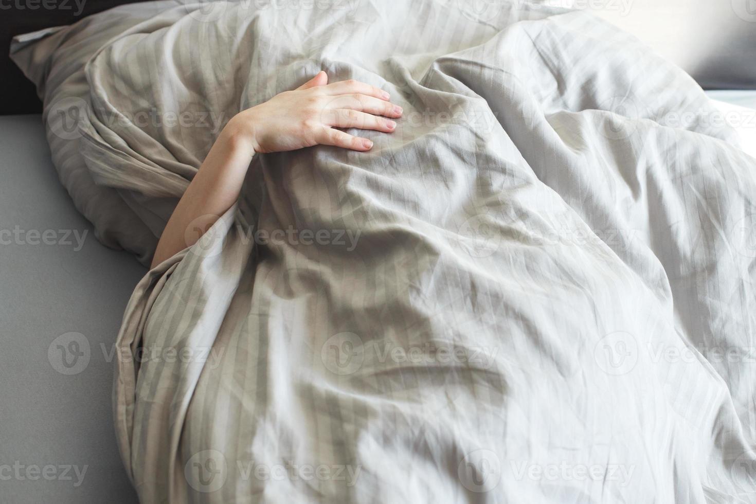 jongen slaap in de bed. kind leugens Aan hoofdkussen en covers zijn gezicht met een deken foto