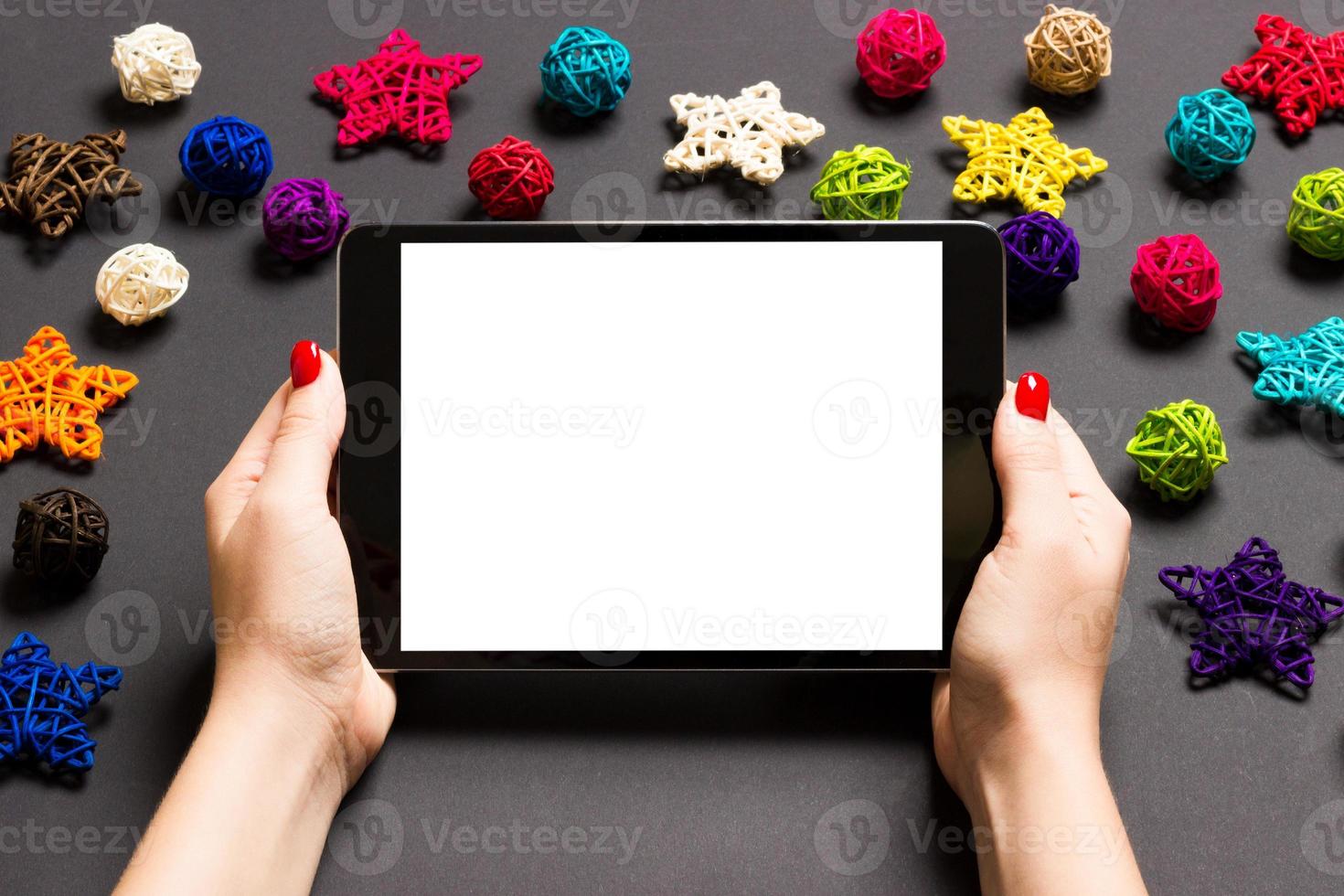 top visie van vrouw Holding tablet in haar handen Aan zwart achtergrond gemaakt van Kerstmis decoraties. nieuw jaar vakantie concept. mockup foto