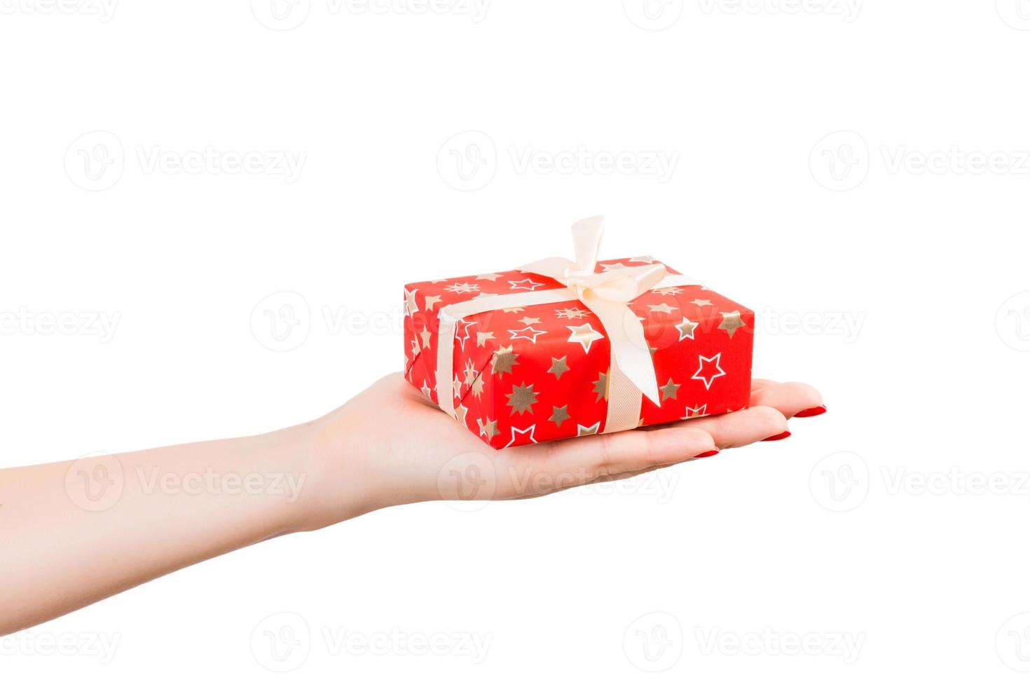 vrouw handen geven verpakt Kerstmis of andere vakantie handgemaakt Cadeau in rood papier met goud lintje. geïsoleerd Aan wit achtergrond, top visie. dankzegging geschenk doos concept foto