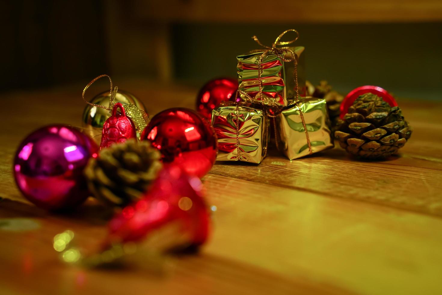 nieuw jaar en Kerstmis geschenk themed decoraties Aan houten achtergrond, bestaande van een gouden geschenk doos. glimmend gekleurde ballen droog pijnboom kegels en klein klokken vrij ruimte voor ontwerp foto