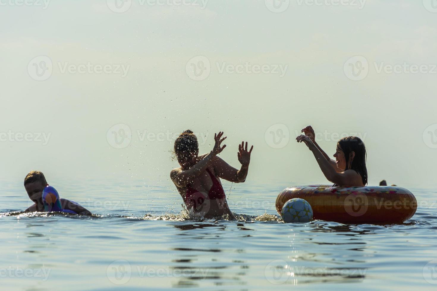 mam en kinderen zwemmen in de zee, plons water en hebben plezier, strand vakantie foto