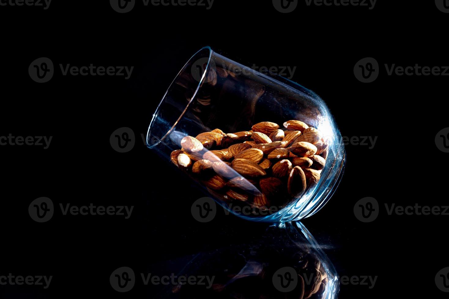 geschild amandel in pot wijnglas emmer Aan een zwart geïsoleerd achtergrond. rij van kommen met amandel noten, voorkant visie. foto