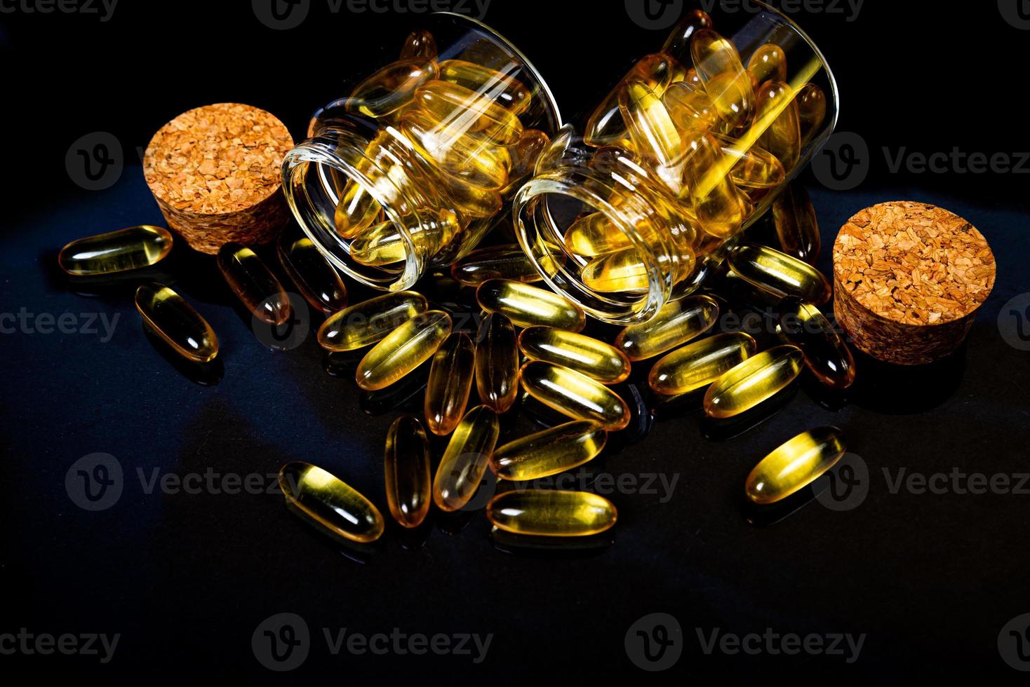 vis olie capsules. geel omega 3 pillen in pot Aan de donker zwart. vis olie capsules in wijnglas glas . in kan. in emmer ampullen foto