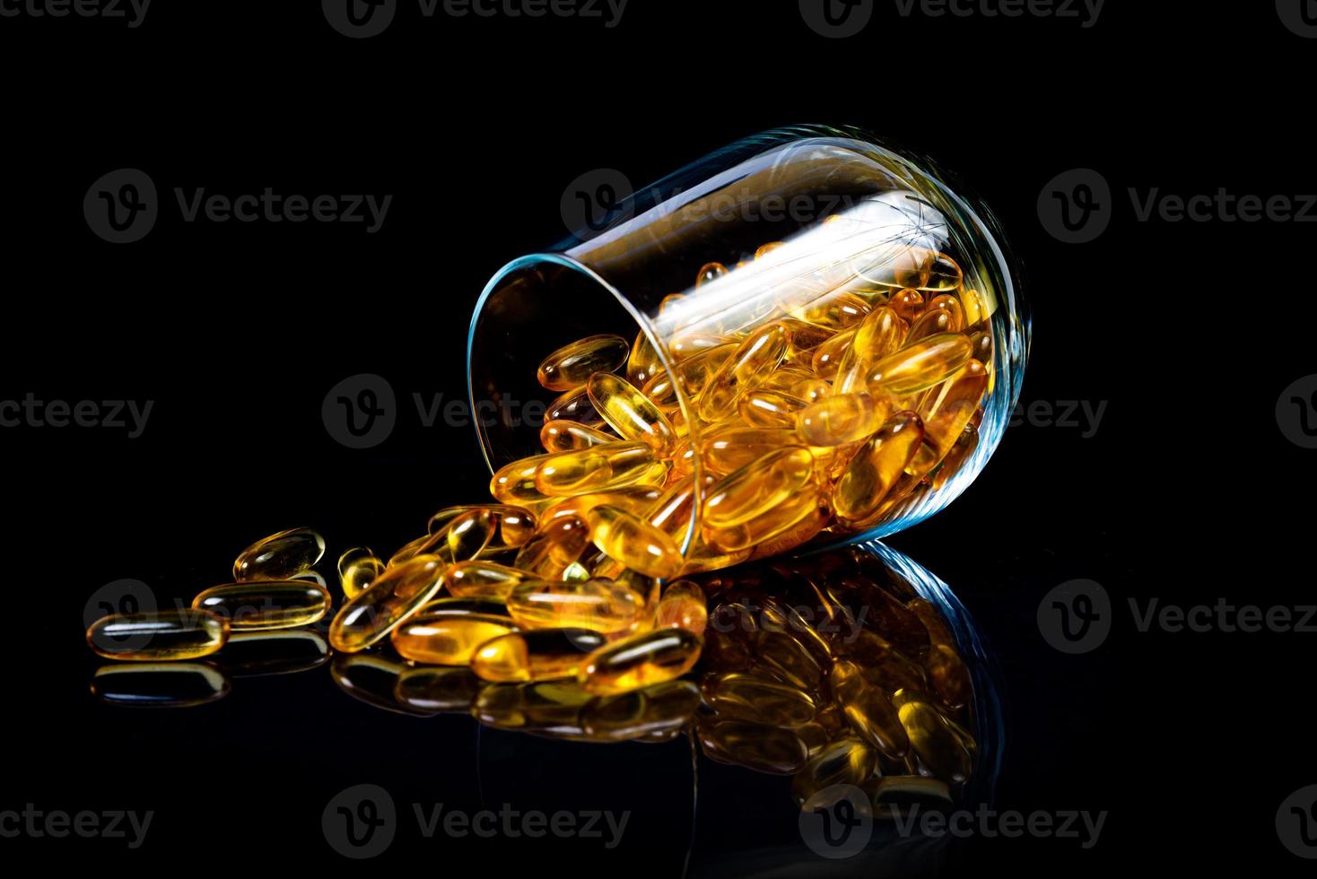 vis olie capsules. geel omega 3 pillen in pot Aan de donker zwart. vis olie capsules in wijnglas glas . in kan. in emmer ampullen foto