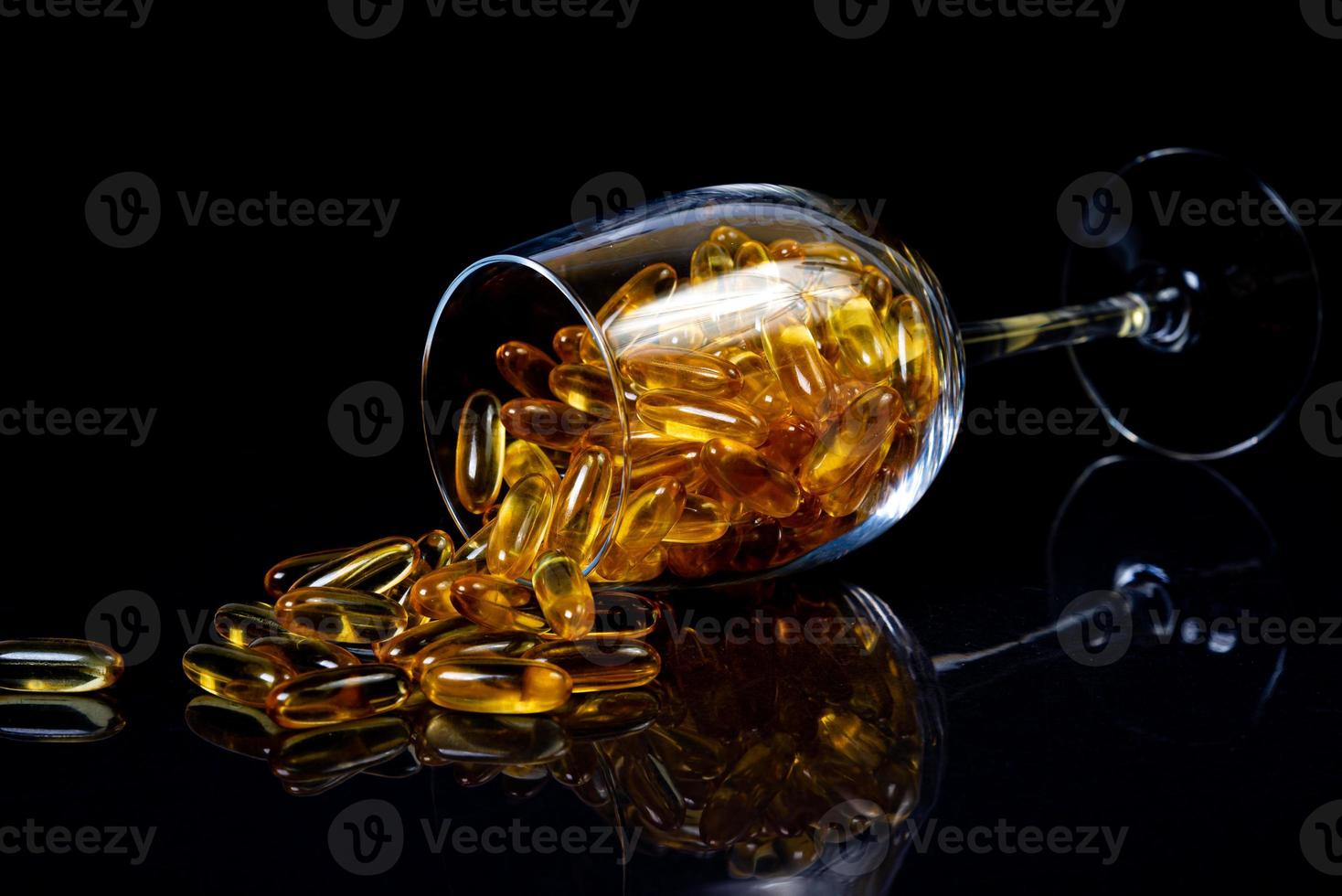 vis olie capsules. geel omega 3 pillen in pot Aan de donker zwart. vis olie capsules in wijnglas glas . in kan. in emmer ampullen foto