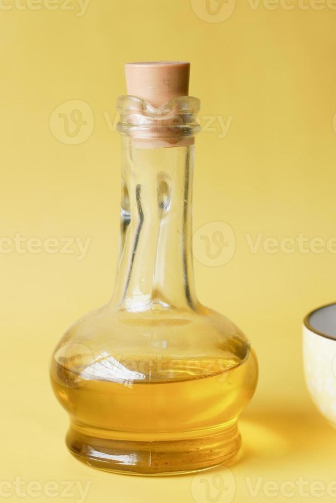 fles olijfolie en olijfbladeren op geel foto
