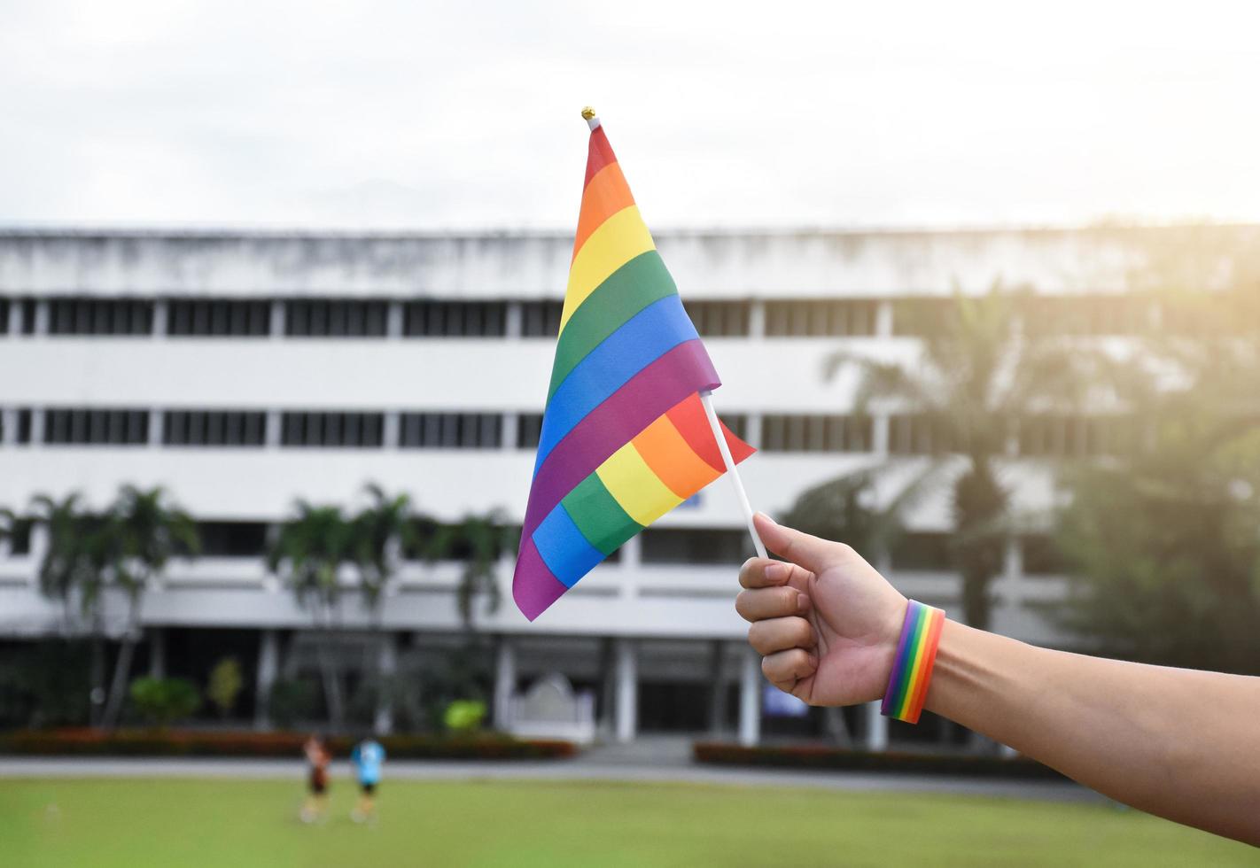 regenboog vlag holing in hand- van Aziatisch homo welke draagt regenboog polsbandje naar telefoontje uit en shows lgbt geslacht verscheidenheid en met inachtneming van geslacht alternatief in de omgeving van de wereld. foto