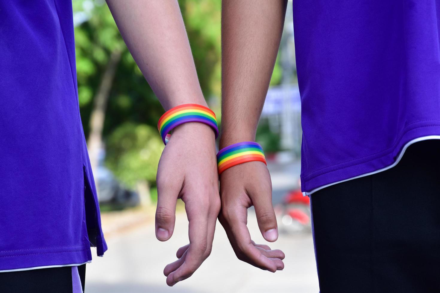 regenboog polsbandje vervelend in hand- van jong Aziatisch homo naar tonen en staan voor geslacht diversiteit, naar respect menselijk rechten in alternatief seks, naar hou op straffen homoseksuelen in sommige religies foto