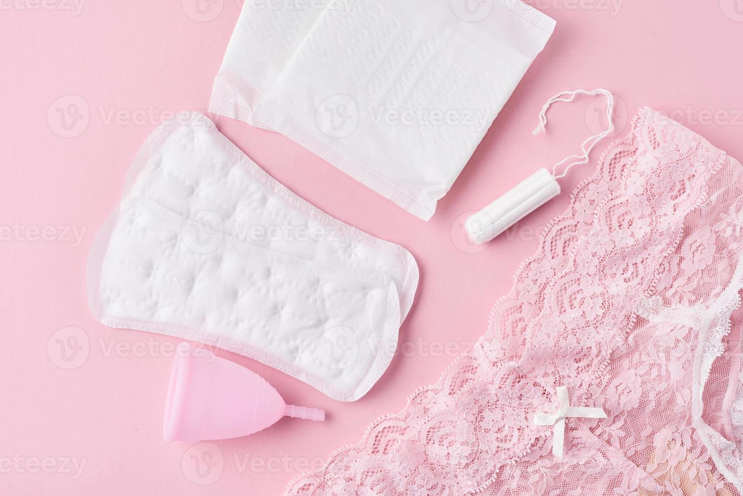 sanitair kussen, menstruatie- beker, tampon en slipje Aan een roze achtergrond foto