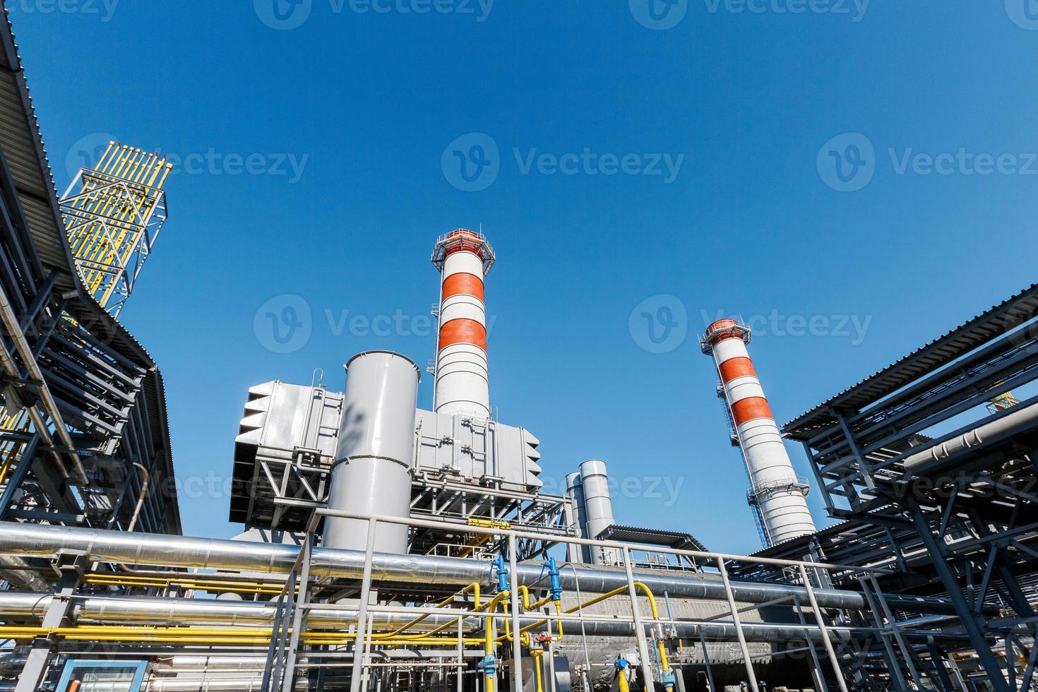 gas- turbine macht fabriek Aan natuurlijk gas- met schoorstenen van rood Wit kleur tegen een blauw lucht Aan een zonnig dag foto