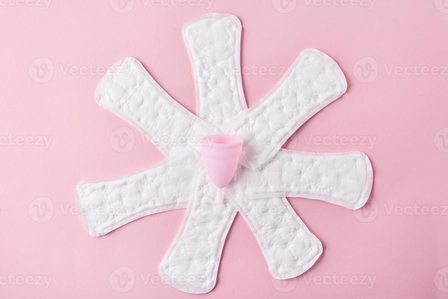 sanitair stootkussens en menstruatie- kop Aan een roze achtergrond foto
