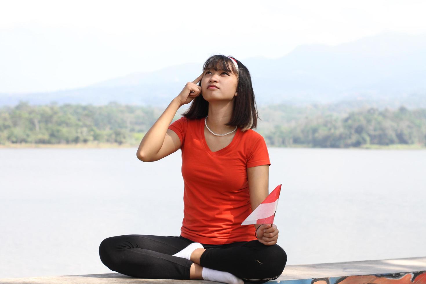 mooi jong Aziatisch vrouw draag- de Indonesisch vlag met een vrolijk gezicht foto