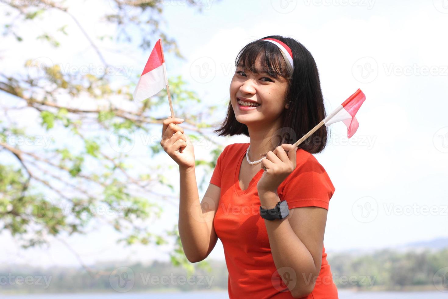 mooi jong Aziatisch vrouw draag- de Indonesisch vlag met een vrolijk gezicht foto