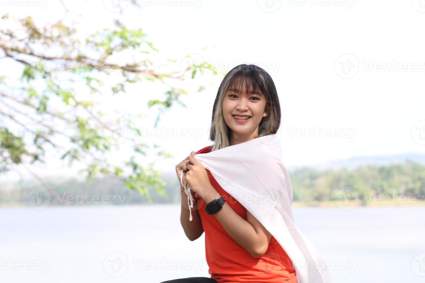 mooi jong Aziatisch vrouw draag- de Indonesisch vlag met een vrolijk gezicht foto