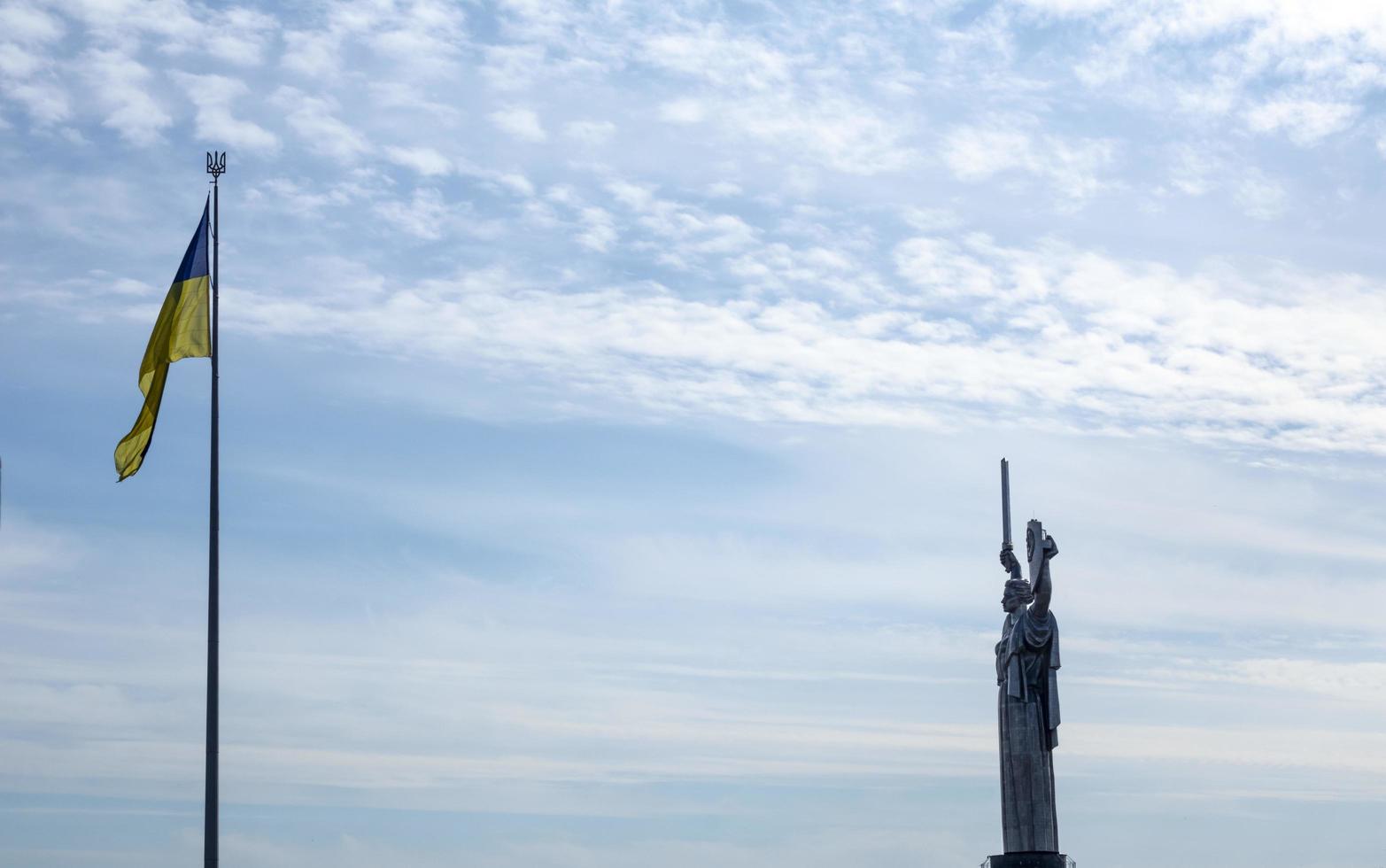 de oekraïens vlag fladderend in de wind tegen de blauw lucht, in de buurt de beroemd standbeeld van de moederland. beroemd bezienswaardigheden, monumenten en monumenten van kiev. Oekraïne, kyiv - oktober 08, 2022. foto