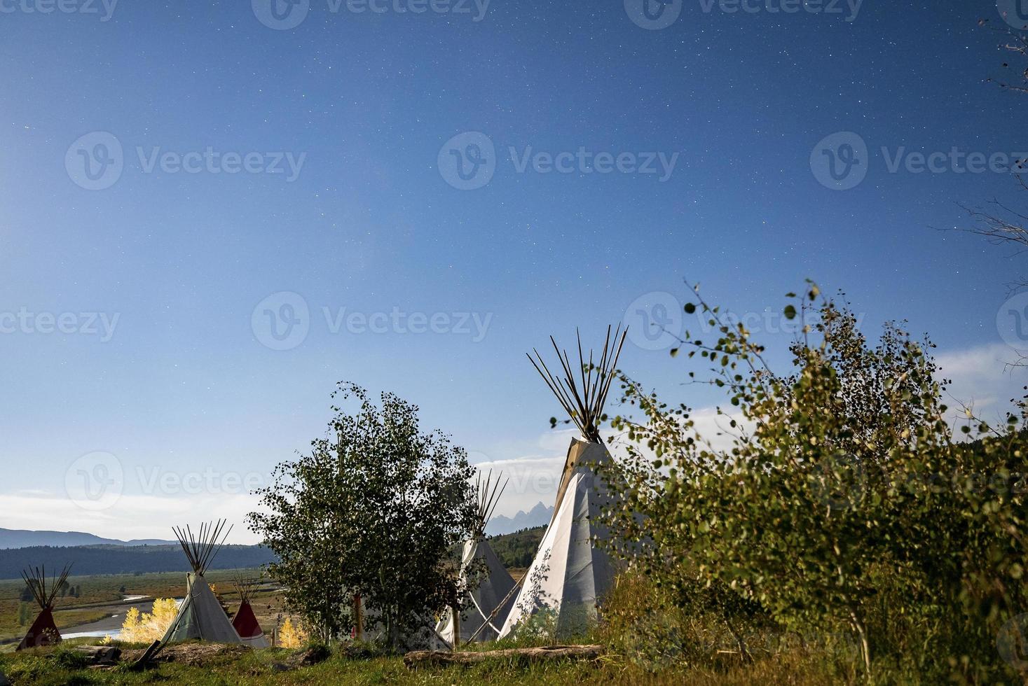 visie van tipi's Aan veld- temidden van bomen met blauw lucht in achtergrond Aan zonnig dag foto